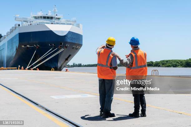 dock control coworkers discussing while looking at ship - dock worker stockfoto's en -beelden