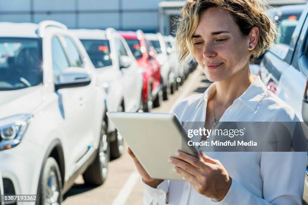 saleswoman taking inventory at car dealership - bilförsäljare bildbanksfoton och bilder