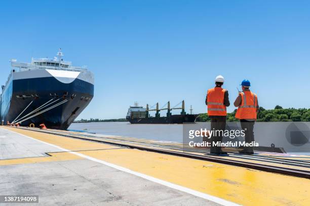 male cargo handler and customs broker looking at cargo ship on river - customs officer stock pictures, royalty-free photos & images