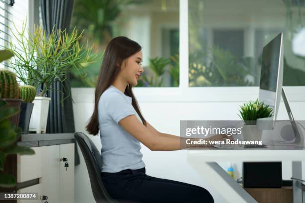 confidence office woman smiling while working at desk in healthy environment - good posture fotografías e imágenes de stock