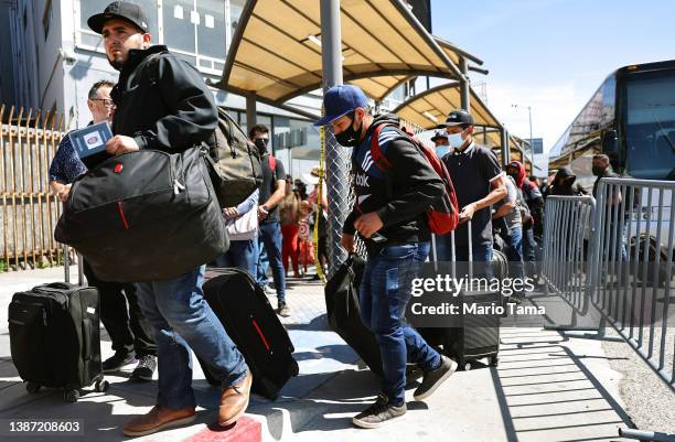 Temporary agricultural workers with H-2A work visas depart from a bus to cross the San Ysidro Port of Entry on their way to seasonal jobs in the...