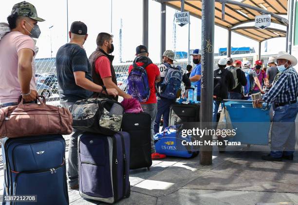 Temporary agricultural workers with H-2A work visas wait in line to cross the San Ysidro Port of Entry on their way to seasonal jobs in the United...