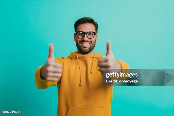 young man wearing eyeglasses showing thumbs up - thumbs up stock pictures, royalty-free photos & images