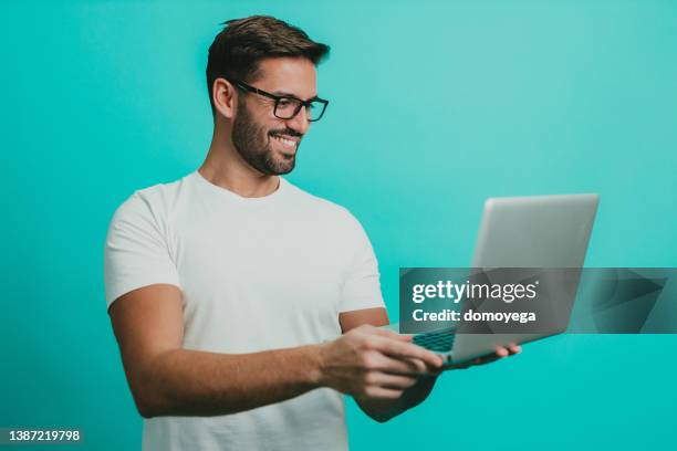 handsome man having a video call on a laptop - laptop coloured background stock pictures, royalty-free photos & images
