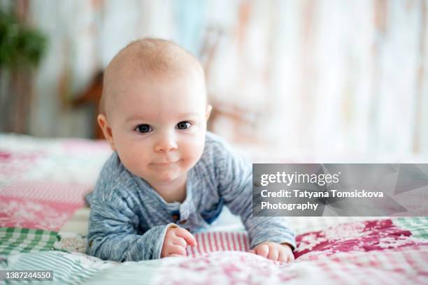 cute little smiling newborn baby boy, playing in bed in the morning - baby touching belly fotografías e imágenes de stock