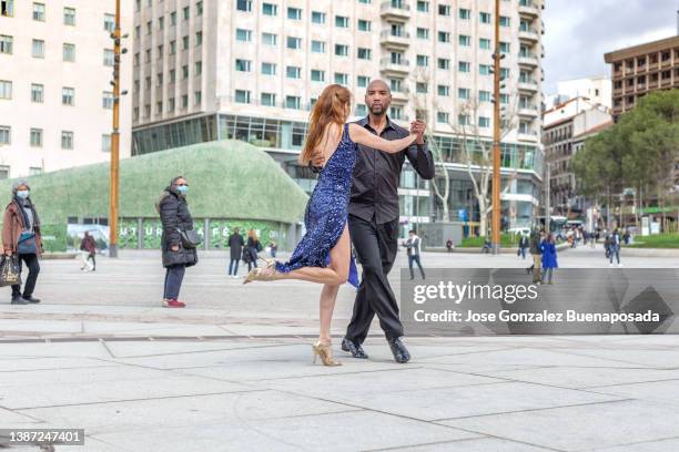 gemischtes und multirassisches tanzpaar tanzt auf der straße, beobachtet von passanten - tango black stock-fotos und bilder