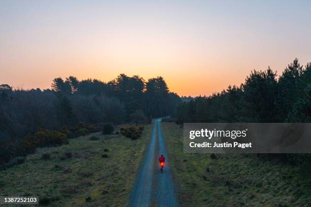 drone view of a cyclist on a gravel trail through the forest at dusk - bicycle top view stock-fotos und bilder