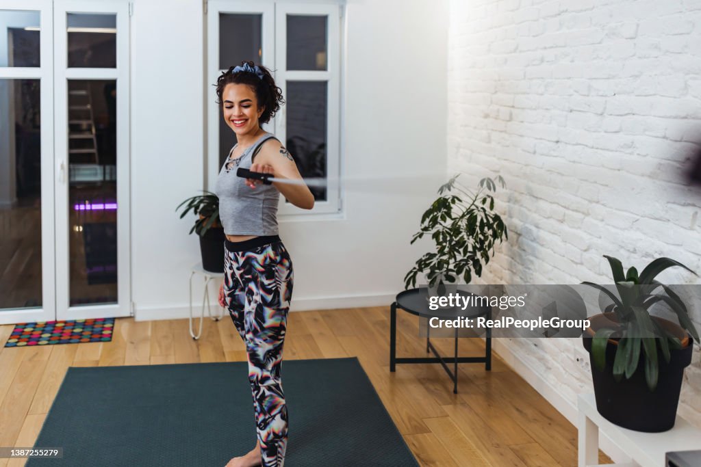 Young Woman during her fitness workout at home with resistance suspension straps