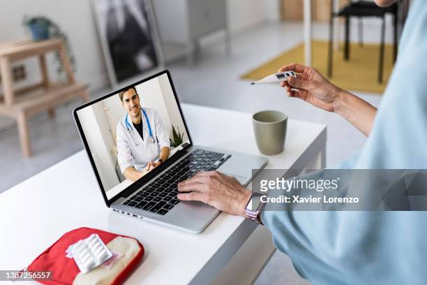 sick woman having a video call with her doctor from home. online medical assistance. - online doctor stock pictures, royalty-free photos & images