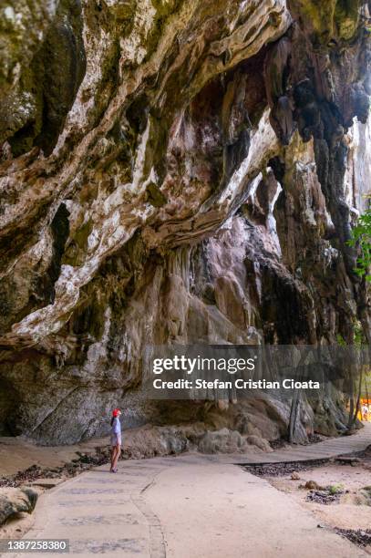 girl looking at  phra nang rock cave on railay island, krabi, thailand - bergsvägg bildbanksfoton och bilder