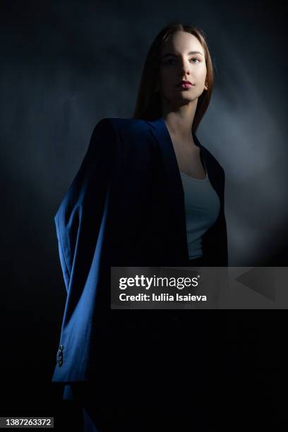 self confident woman in suit in dark studio - portrait dark background stock pictures, royalty-free photos & images