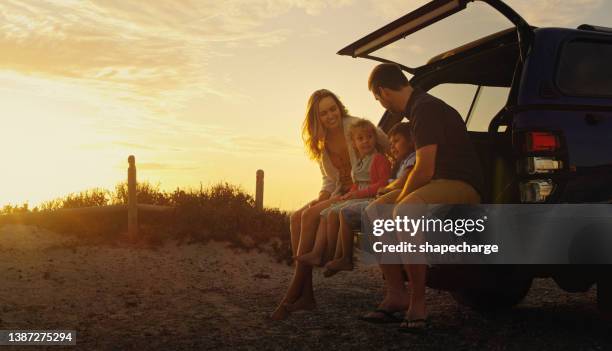 foto de una familia sentada en la parte trasera de su vehículo mientras está en la playa - family holiday fotografías e imágenes de stock