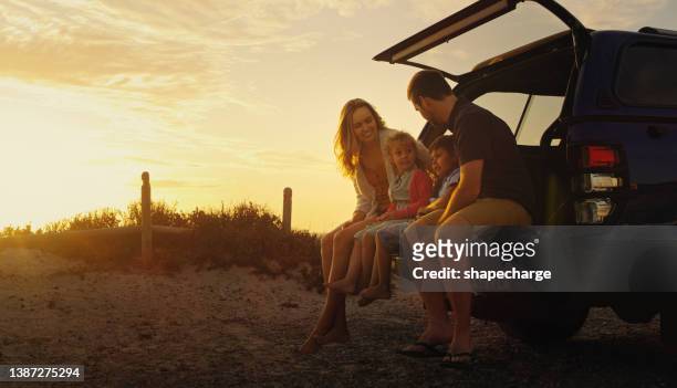 shot of a family sitting at the back of their vehicle while at the beach - car imagens e fotografias de stock