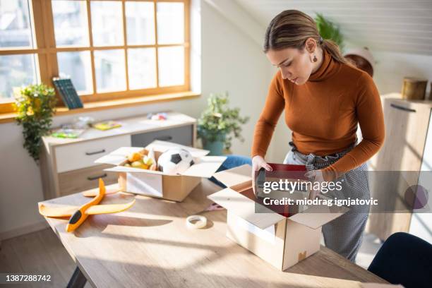 female volunteer packing books for donation into cardboard box - clear donation box stock pictures, royalty-free photos & images