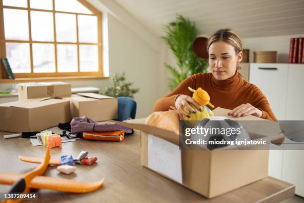 volontariato femminile premuroso che imballa i giocattoli in una scatola di cartone per la donazione - elemosina oggetto religioso foto e immagini stock