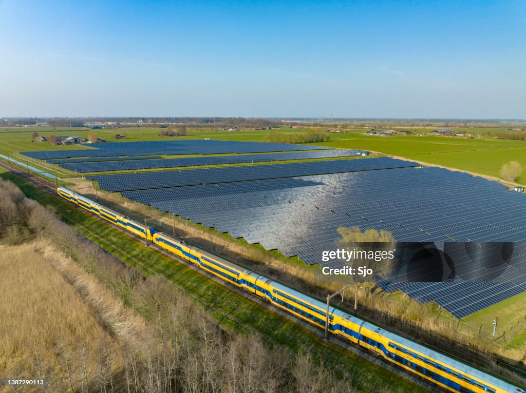 Train of the Nederlandse Spoorwegen NS driving past a field of solar panels