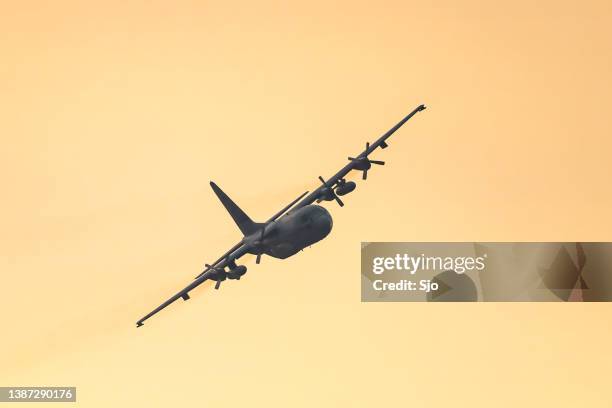 lockheed c-130 hercules military airplane flying in mid air during sunset - lockheed c 130 hercules stock pictures, royalty-free photos & images