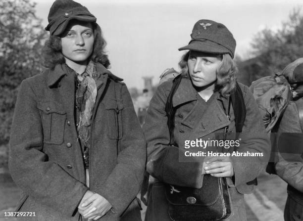 Two German women prisoners of war from a Wehrmachthelferin unit, walk into captivity after surrendering to soldiers from the United States Seventh...