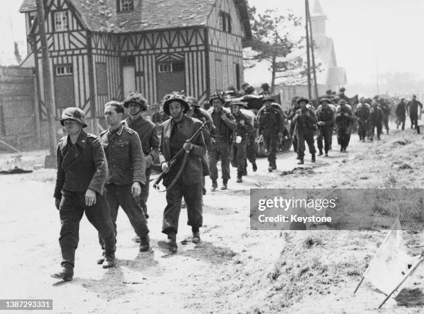 Some of the first German Wehrmacht prisoners of war captured by the invading Allied forces on D-Day being escorted back through the village of La...