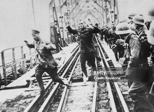 Soviet Red Army prisoners of war captured during Operation Barbarossa, the Nazi German invasion of Russia are forced to cross a railway bridge with...