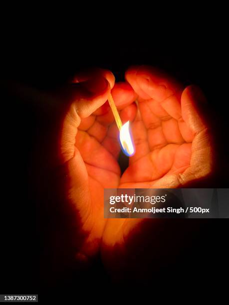 light in the dark hands,close-up of hand holding illuminated cigarette lighter against black background,amritsar,punjab,india - マッチ棒 ストックフォトと画像