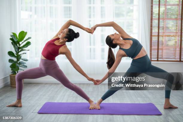 Two Young Women Practicing Couple Yoga Poses At Home High-Res