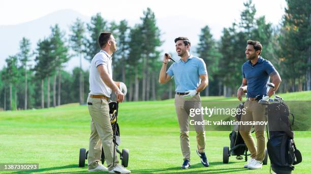 group of male golfer friends, playing golf on a beautiful sunny day, talking and smiling while standing on golf course - business pitch stock pictures, royalty-free photos & images