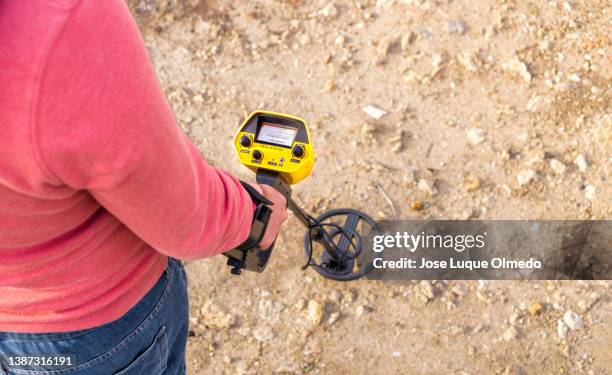 top view of person using a metal detector to find objects in the countryside during a sunny day with copy space right. - schatzoeken stockfoto's en -beelden
