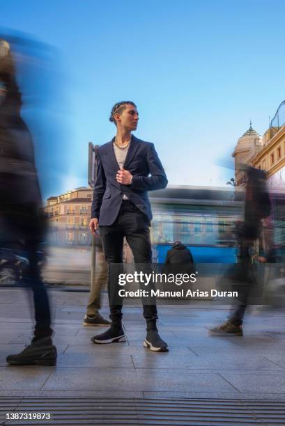 boy posing in casual suit in the city while moving people pass by. - anzug ausland stock-fotos und bilder