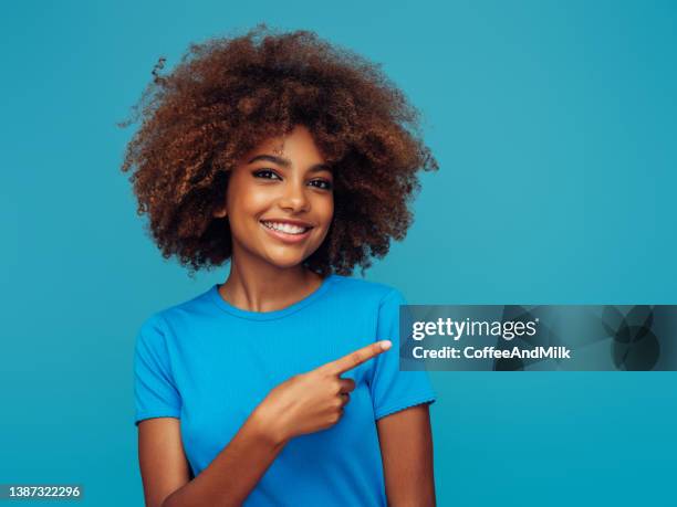 linda garota sorridente com penteado encaracolado - apontando sinal manual - fotografias e filmes do acervo