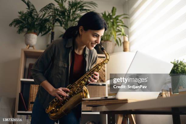 engagierte saxophonistin, die mit ihrem musiklehrer einen online-kurs über einen laptop hat - sax stock-fotos und bilder