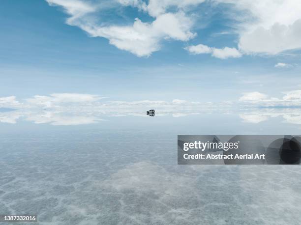 majestic drone image showing a 4x4 crossing salar de uyuni during the day, bolivia - salar de uyuni stockfoto's en -beelden