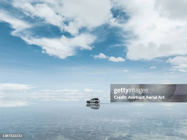 low angle drone shot showing a 4x4 driving across salar de uyuni in the wet season, bolivia - drone isolated stock pictures, royalty-free photos & images