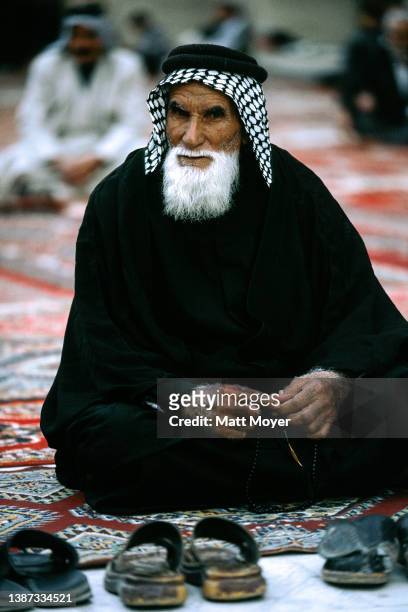 Allah Abdel Amir a physics teacher at the Imam Ali school, prays as the sun reflects off the shrine on November 13, 2003 in Najaf, Iraq. He comes to...