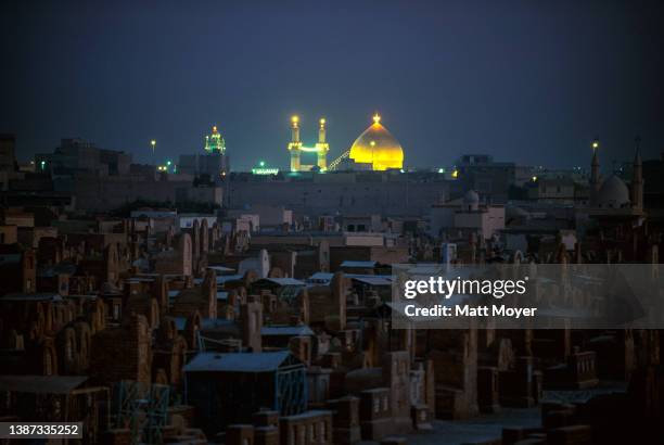 The Imam Ali Shrine can be seen lit up behind the Valley of the Peace Cemetery on October 5, 2003 in Najaf, Iraq. Najaf is the holiest city for the...