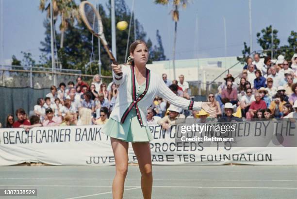 American tennis player Chris Evert, wearing a white cardigan over a pale green tennis dress, preparing for her final against Evonne Goolagong at the...