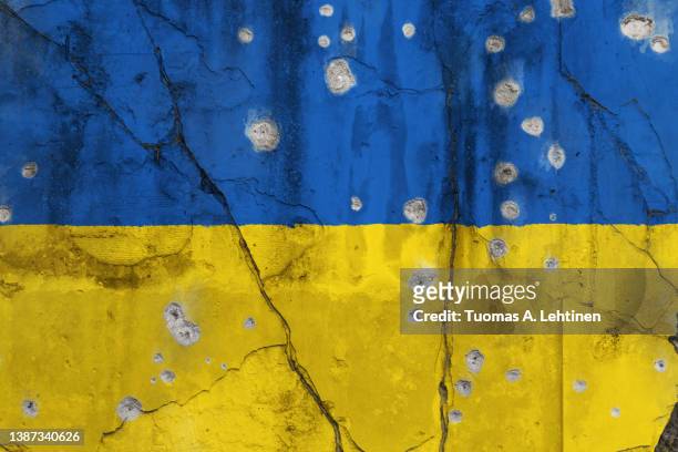 full frame photo of a weathered flag of ukraine painted on a cracked wall with bullet holes. - kulhål bildbanksfoton och bilder