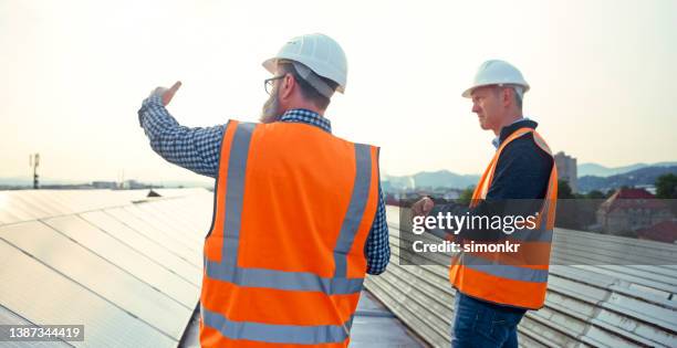 ingenieros de pie en una granja solar - suministro de energía fotografías e imágenes de stock