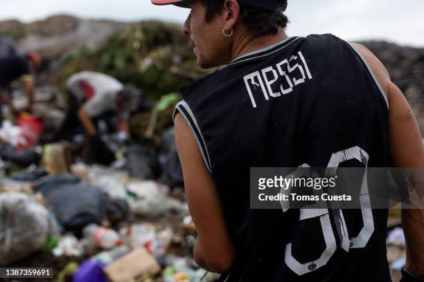 Man wearing a jersey of Argentine soccer player Lionel Messi works separating rubbish on March 23, 2022 in Lujan, Argentina. Despite the official...