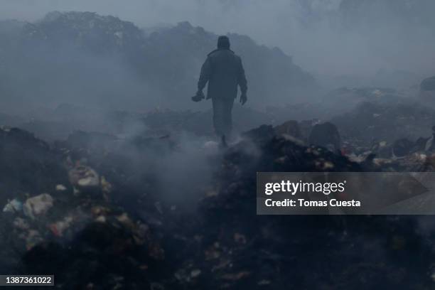 Man works sorting trash in Lujan's open air dump on March 18, 2022 in Lujan, Argentina. Despite the official announcements of a plan to reconvert the...