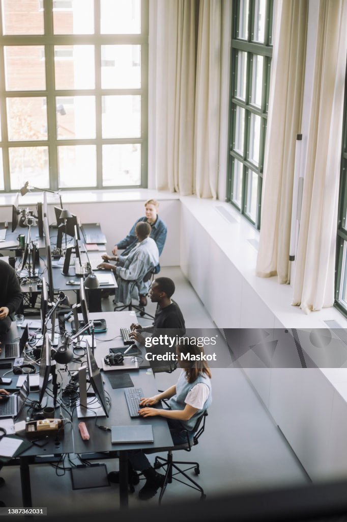 High angle view of multiracial programmers working on computers at desk in office