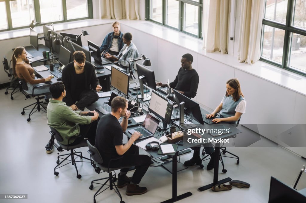High angle view of male and female programmers working on computers at desk in office