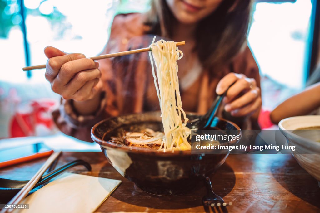 Young Asian woman enjoying Japanese noodle soup in a Japanese restaurant