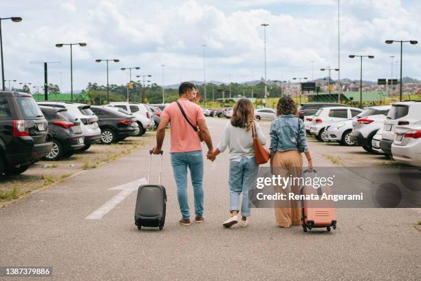 latin family walking with suitcase at airport parking - luggage trolley stockfoto's en -beelden