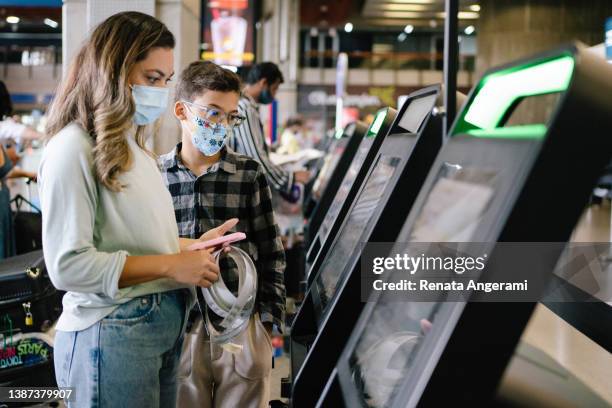 madre e hijo haciendo el check-in en el tótem del aeropuerto - tótem fotografías e imágenes de stock