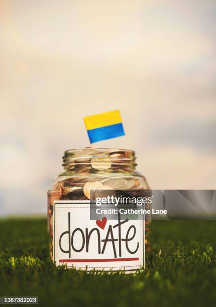 donation jar with coins and ukrainian flag. fundraising concept. - fundraising stock-fotos und bilder