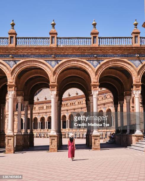 woman walking towards arch at plaza de espana in seville - seville stock pictures, royalty-free photos & images