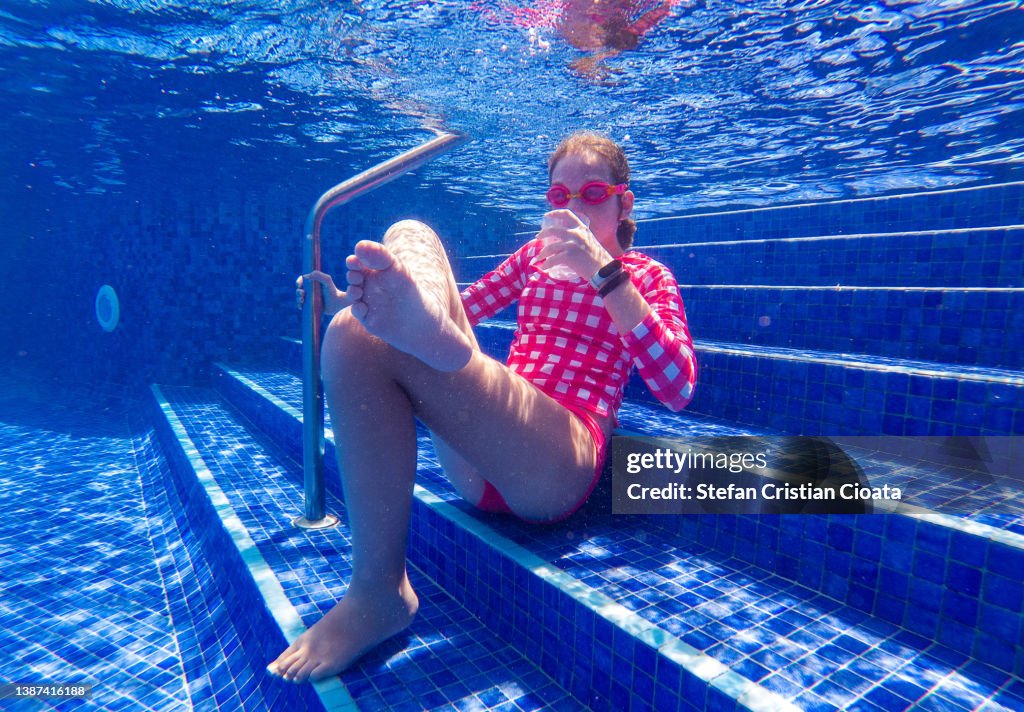 Girl with drinking glass underwater.