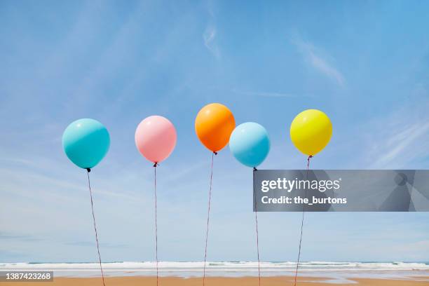 five colorful balloons in a row at beach against blue sky - sea happy birthday no people stock pictures, royalty-free photos & images