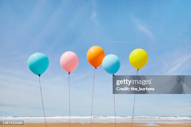 five colorful balloons in a row at beach against blue sky - balloons in sky stock pictures, royalty-free photos & images